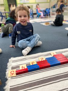 a smiling child learning how to count and recognizing numbers 